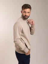 Campera color beige de tejido de punto con cierre frontal y cuello alto.