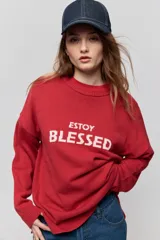 Sweater de punto marrón de tejido liviano y calce relajado, con hombros caídos, cuello redondo y puños y cintura en rib. Cuenta con una estampa tejida en el frente con la frase "Estoy Blessed" en color amarillo.