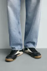 Zapatilla de cordones estilo retro, color negro con detalles en blanco y suela de goma color caramelo.