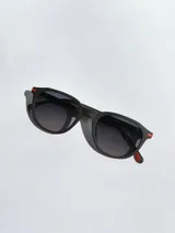 Lentes de sol Osten modelo Maui, con armazón negro de diseño redondeado y detalles en color naranja en las patillas. Cuentan con cristales polarizados con protección UV 400.