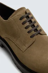 Zapato de cordones tipo derby en piel con acabado serraje color verde militar. Horma redonda y suela track negra a contraste.