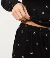 Pijama de dos piezas confeccionado en tejido rib acanalado con estampado floral. Incluye una blusa de manga larga con cuello redondo y cierre frontal de botones, y un pantalón largo con cintura elástica.