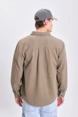 Sobrecamisa de gabardina verde militar, de corte recto, con mangas largas, bolsillos frontales con solapa y botones, y cierre frontal abotonado.