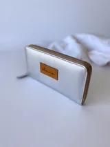 Billetera plateada de cuero con cierre metálico, monedero interno y capacidad para billetes extendidos.