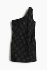 Vestido corto negro con estampado de lunares blancos, escote asimétrico de un solo hombro y tira ancha decorativa que cae desde el hombro.
