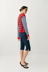 Chaqueta de punto con cuello redondo y mangas largas, con diseño de rayas horizontales en colores rojo, celeste y azul marino, y cierre frontal con botones.