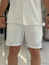 Bermuda blanca de tejido texturizado, con pequeño bordado oscuro en la parte inferior izquierda.