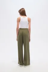 Pantalon deportivo de corte ancho y tiro alto, color verde oliva, con cintura elástica y una línea vertical blanca lateral en cada pierna.