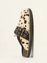 Zueco de cuero vacuno con estampado animal print tipo vaca, con hebilla decorativa metálica con ojales y suela de corcho con vira reforzada.