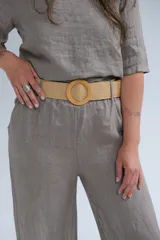 Pantalón de lino color visón, de corte recto y tiro medio. Incluye cinturón beige de soga con hebilla circular de madera.