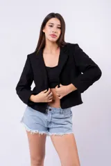 Blazer negro de corte estructurado, con solapas de muesca, manga larga con puños doblados y bolsillos frontales.