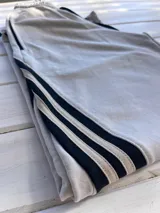 Pantalón deportivo color naranja con las icónicas tres rayas blancas laterales características de la marca Adidas.
