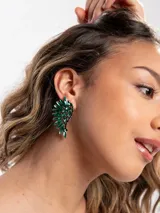 Aros tipo ear cuff colgantes con diseño de alas decoradas con cristales facetados de color verde esmeralda y estructura oscura.