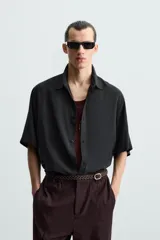 Camisa de corte relajado confeccionada en tejido con mezcla de modal, con cuello solapa, manga corta y cierre frontal de botones.