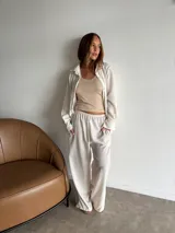 Camisa de manga larga color crudo o blanco roto, con textura visible, corte holgado y cuello camisero. Se lleva abierta sobre un top beige de punto.