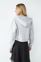 Campera con capucha y cierre frontal de cremallera, confeccionada en tejido gris melange con bolsillos estilo canguro y puños y bajo de canalé.
