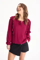 Blusa de viscosa color bordó con escote en V y tira ajustable para anudar, manga larga abullonada y detalles de volados en los hombros.