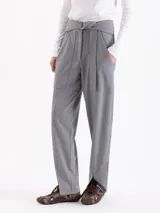Pantalón de punto liso color gris, de corte recto y silueta relajada. Presenta cintura alta con cinto integrado, bolsillos aplicados en el delantero y tajos frontales en el ruedo.