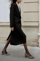 Zapato destalonado de piel con pelo, con estampado animal print. Presenta tacón alto ancho, tira trasera ajustable con hebilla metálica y acabado en punta cuadrada.