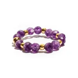 Anillo elástico con cuentas facetadas de color violeta y cuentas doradas.