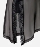 Blusa ajustada de tul negro con diseño asimétrico de un solo hombro. Presenta mangas largas transparentes, fruncido lateral y una aplicación vertical de encaje que aporta textura.