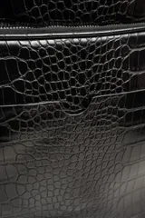 Mochila negra con textura símil cuero de cocodrilo, con dos compartimentos principales con cierre y asa de mano en la parte superior.