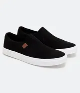 Championes tipo slip on marca Viko, de color negro con suela de goma blanca. Presenta un diseño minimalista sin cordones con paneles elásticos laterales y un pequeño detalle de etiqueta en color marrón.