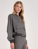 Camperita tipo bomber color beige claro, con cuello redondo acanalado, cierre frontal con broches metálicos y bolsillos delanteros con tapa. Los puños y el bajo son acanalados.