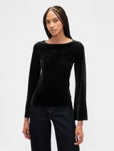 Remera de terciopelo color negro, con cuello bote y mangas largas ligeramente acampanadas.
