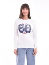 Remera de manga larga color blanco, con cuello redondo y estampa frontal estilo universitario con el número 86 en azul desgastado y detalles en rojo.