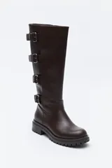 Bota de caña alta tipo biker en símil cuero color marrón oscuro. Presenta múltiples tiras horizontales con hebillas metálicas laterales y una suela robusta con relieve.