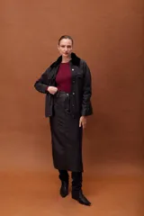 Falda larga de cuero ovino con efecto gastado, diseño tipo jeanera con bolsillos frontales y traseros, y aberturas laterales.