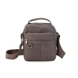 Morral de tela canvas color verde oliva, con correa regulable y asa de mano. Tiene dos bolsillos frontales con cierre, llavero exterior, bolsillos internos y bolsillo trasero con cierre.