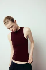 Top de punto color crema, sin mangas, con cuello redondo y corte ajustado.