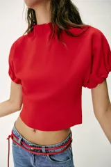 Top de punto color azul marino, con cuello redondo y mangas cortas abullonadas con acabados elásticos fruncidos.