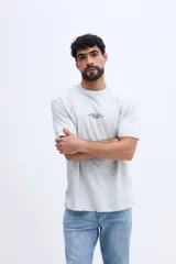 Remera oversize color gris melange, de manga corta y cuello redondo, con pequeño estampado frontal en el pecho.