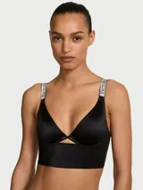 Bralette tipo longline demi color negro, confeccionado en suave microfibra con aros y sin forro. Presenta un escote pronunciado en V con detalle de aberturas entrecruzadas en el centro y tirantes ajustables con pedrería brillante con el logo.
