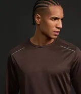 Remera deportiva de manga larga con cuello redondo, confeccionada en tejido técnico Dry Fit. Presenta un diseño liso en color negro con detalles reflectantes en los hombros.