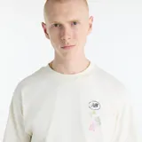 Remera de algodón New Balance International Stamp, color blanco off-white, de corte holgado, manga corta y cuello redondo. Presenta un pequeño estampado gráfico en el pecho con diseño de sellos internacionales y logo de la marca.