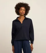 Campera deportiva negra confeccionada en microfibra pesada, con cuello alto doblado, cremallera delantera con cordón en el tirador y puños ajustados.