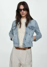 Chaqueta de jean clásica con cuello, cierre frontal de botones metálicos, bolsillos de parche con solapa en el pecho y bolsillos laterales. Presenta un lavado claro y mangas largas con puños abotonados.