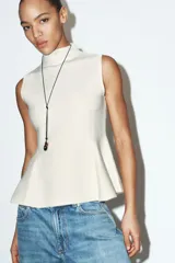 Top de punto sin mangas con cuello subido y diseño entallado con bajo en evasé tipo peplum.