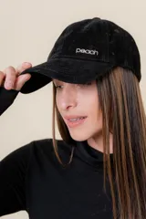 Gorra de diseño clásico con visera curva, confeccionada en textura suave tipo gamuza. Presenta un logo metálico con la palabra Peach en la parte frontal y cuenta con un sistema de ajuste posterior.