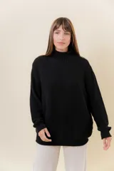 Polera de tejido de punto con textura marcada, color negro, de calce oversize, cuello alto, hombros caídos y terminaciones acanaladas en puños y ruedo.
