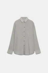 Camisa fluida de corte oversize con estampado de rayas verticales finas, cuello solapa, manga larga con puños abotonados y bolsillo de plastrón en el pecho.