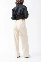 Camisa negra de corte entallado con cuello clásico y cierre frontal de botones. Presenta un diseño con elástico en la cintura que marca la silueta y mangas largas con puños elásticos.