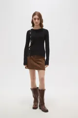 Remera de algodón de calce ajustado, con cuello redondo y manga larga. Presenta una hilera de botones decorativos dorados en el hombro y lateral derecho.