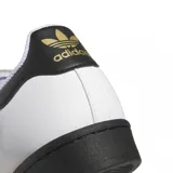 Championes adidas modelo Superstar ADV, de diseño clásico con exterior de cuero blanco, las icónicas tres tiras laterales en negro, puntera de goma negra y suela plana también en color negro.