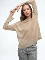 Sweater de tejido fino y semitransparente con hilo brillante. Presenta cuello redondo, hombros caídos y mangas largas amplias con un ajuste relajado y caída fluida.