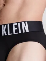 Pack de tres slips para hombre, confeccionados en microfibra de poliéster reciclado y elastano. El slip visible es de color gris liso con cinturilla elástica negra que lleva el logo de Calvin Klein en gris.